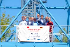 Vertretende von SLV Halle, DVS Zert und WTI Harbin stehen auf dem SLV-Turm. Vor ihnen hängt ein Banner mit der Aufschrift "40 Jahre Chinesisch-Deutsche Kooperation". 