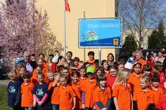 Grundschulkinder vor dem Elbkinderland-Schild mit Rolf Zuckowski und einem Kuscheltier-Storch