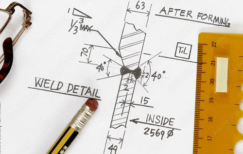 Technische Zeichnung mit markierten Schweißdetails, daneben liegen ein Bleistift, ein Lineal und eine Brille.