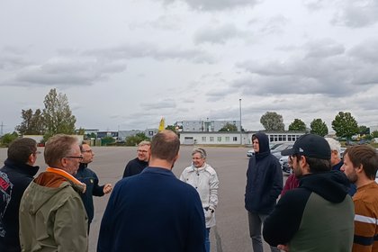 Gruppe aus zehn Personen im Gespräch auf Übungsplatz