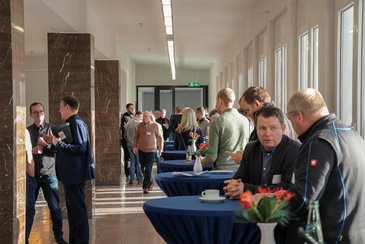 Menschen unterhalten sich an Stehtischen während einer Pause in einem hellen Foyer